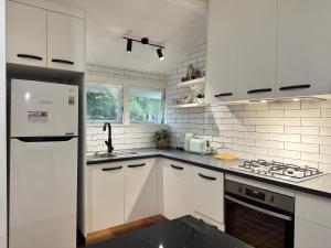 Cosy Cottage 4173 في بريزبين: مطبخ أبيض مع حوض وثلاجة