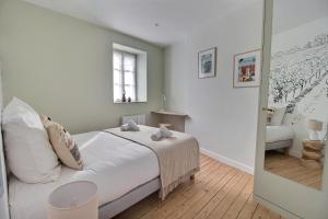 a bedroom with a bed with white sheets and a window at Le Logis Saint-Ursin by PRIMO C0NCIERGERIE in Bourges