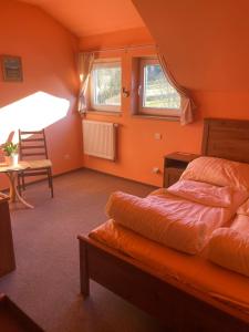 - une chambre avec des murs orange, un lit et une table dans l'établissement Penzion D'Artagnan, à Kořenov
