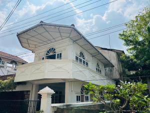 a white house with a balcony on top of it at Sarojeni Apartments and Rooms in Negombo