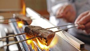 a person cooking food on a grill with tongs at Ashizuri Kokusai Hotel in Tosashimizu +45 photos
