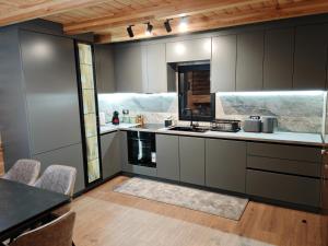 a kitchen with grey cabinets and a table and chairs at Boga Chalet in Bogë