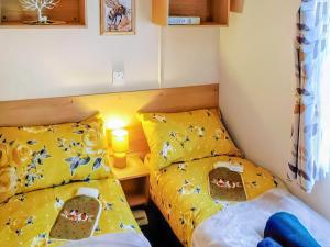 two beds in a small room with yellow sheets at The Hive in Hawick