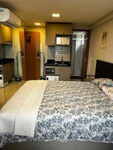 a bedroom with a large bed and a kitchen at Flat 201 Paradise in João Pessoa