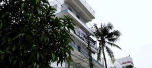 un grand bâtiment blanc avec un palmier devant dans l'établissement Rajdhani Hospitality, à Kazhakuttam