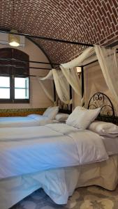 a bedroom with two beds with white sheets and curtains at El Juneina Villas - Luxury Boutique Villas Near Valley of the Kings in Luxor