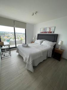 ein Schlafzimmer mit einem Bett und einem Stuhl und einem Fenster in der Unterkunft Departamento con vista a las Dunas y playa in Concón + 8 Fotos