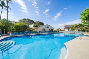 a large swimming pool with blue chairs and a building at Maui Hill 66 · MHL 66 3BD Condo Across from Keawakapu Beach & St in Wailea