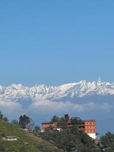 a building on a hill with snow covered mountains in the background at Hotel Pigeon Prince in Nagarkot +10 photos