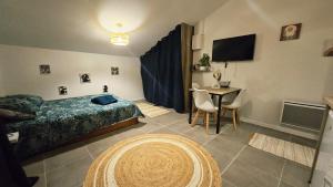 a bedroom with a bed and a table and a television at Studio cosy au calme , Boé in Boé