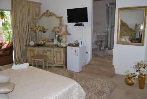 1 dormitorio con cama, espejo y nevera en Ronique's Guest House, en Rustenburg