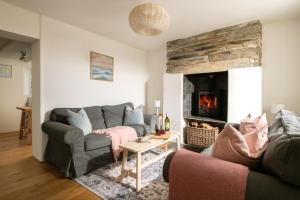 ein Wohnzimmer mit Couch und Kamin in der Unterkunft 1 Rock Cottages in Treknow