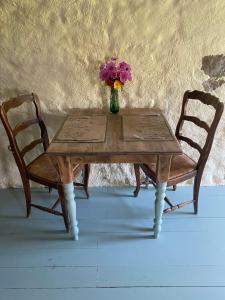 a vase of flowers sitting on a wooden table with two chairs at La Criberie in Saint-Ellier-du-Maine