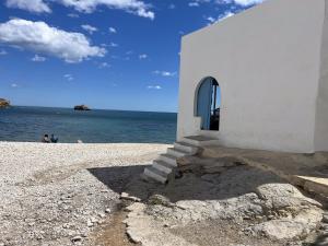 a white building on a rocky beach with the ocean at Calamora-Moraira in Moraira