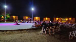 eine Gruppe von Menschen, die nachts auf Stühlen am Strand sitzen in der Unterkunft Dune safari camp & resort in Sām