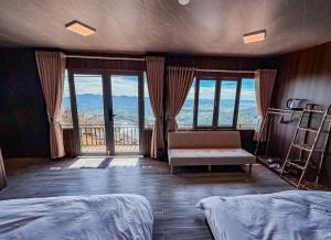 ein Schlafzimmer mit zwei Betten und einer Couch und Fenstern in der Unterkunft Rio Skyhouse in Ấp Trạm Hành