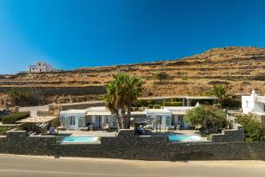 a house with palm trees in front of a hill at Efthymia apartments in Faros