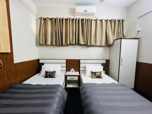 two beds in a small room with a window at Karachi Inn PECHS in Karachi