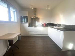 eine Küche mit weißen Schränken und einem Holzboden in der Unterkunft Maison rénovée avec jardin, wifi, BBQ, parking, à 250m de la mer - Pleumeur-Bodou - FR-1-368-14 in Pleumeur-Bodou