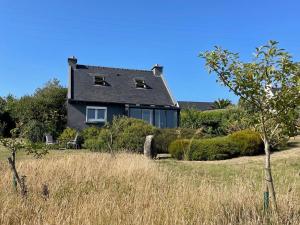ein Haus auf einem Hügel mit einem Feld und Bäumen in der Unterkunft Maison rénovée avec jardin, wifi, BBQ, parking, à 250m de la mer - Pleumeur-Bodou - FR-1-368-14 in Pleumeur-Bodou