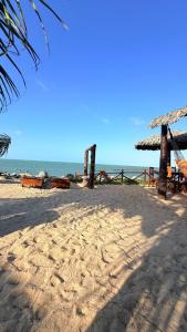 a beach with a straw hut and the ocean at Pousada Ap in Acaraú