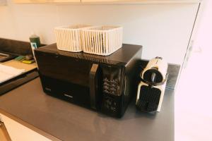 a microwave with two baskets on top of it on a counter at Appartement lumineux et calme sur la Route des vins in Guebwiller