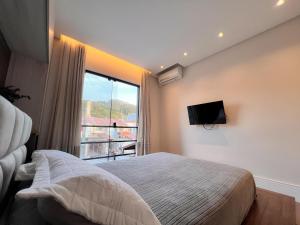 um quarto com uma cama e uma janela grande em Casa com Jacuzzi próximo ao teleférico, aquário, Greenvalley e praia! em Camboriú