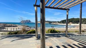 a view of the beach from a wooden pergola at Calamora-Moraira in Moraira