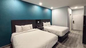 a hotel room with two beds and a blue wall at Studio 6 Houston, TX - Westchase in Houston
