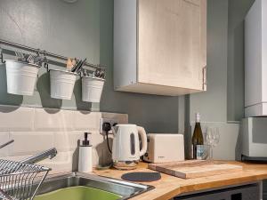 a kitchen with buckets on the wall above a sink at Parsley Cottage in Tideswell