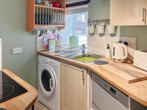 a kitchen with a sink and a washing machine at Parsley Cottage in Tideswell