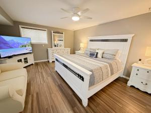 a bedroom with a white bed and a flat screen tv at Lakefront Home 5BD3BA DockGrillsDeckKayaks-16 in Sunrise Beach