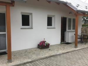 a white house with a porch with a potted plant at Pokoje przy strumyczku in Krobica