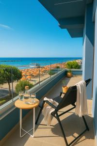 una silla y una mesa en un balcón con vistas a la playa en Frontemare Appartamenti e Camere ELISABETTA, en Cesenatico
