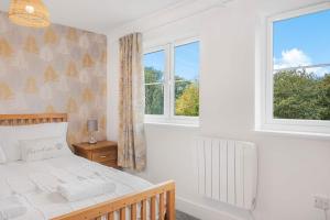 a bedroom with a bed and two windows at The Roost Group - 5 Bed House Hot Tub Near Beach in St. Leonards