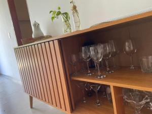 サン・ミゲル・ドス・ミラーグレスにあるCasa 2 quartos com área verde AnaManô Suitesの木製の棚(ワイングラス付) +8枚の写真