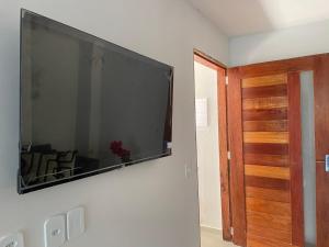 サン・ミゲル・ドス・ミラーグレスにあるCasa 2 quartos com área verde AnaManô Suitesの壁に掛けられた大型の薄型テレビ