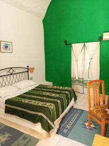 a green bedroom with a bed and a chair at Hotel Dakyanus in Tataouine