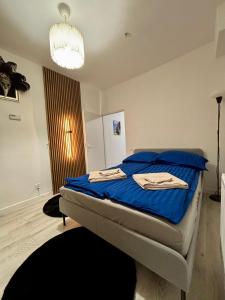 een slaapkamer met een bed met blauwe lakens en een kroonluchter bij Elephant Studio in Wrocław