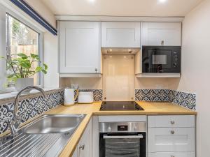 a kitchen with white cabinets and a sink at The Cottage At Number One in Caerwys