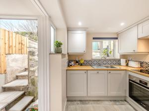 a kitchen with white cabinets and a sink at The Cottage At Number One in Caerwys