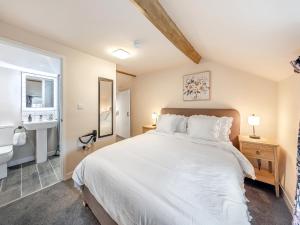 a bedroom with a large white bed and a bathroom at The Cottage At Number One in Caerwys +9 photos
