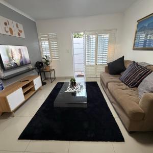 Una sala de estar con un sofá y un televisor en Cozy Retreat with a Pool!, en Cape Town 9 fotos más
