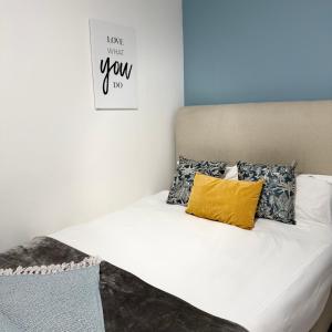 una cama con una almohada amarilla y un cartel en la pared en Cozy Retreat with a Pool!, en Cape Town