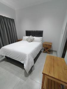 1 dormitorio con cama blanca y mesa de madera en Atloch, en Kimberley