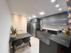 uma cozinha com balcões pretos e aparelhos de aço inoxidável em Casa com Jacuzzi próximo ao teleférico, aquário, Greenvalley e praia! em Camboriú