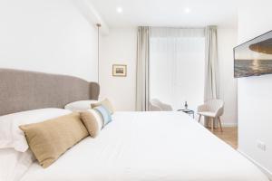 a white bedroom with a bed and a television at Feel Boutique Rooms in Oristano