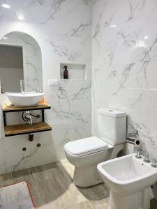 a white bathroom with a toilet and a sink at Village De Las Sierras in Sierra de la Ventana