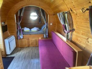 ein kleines Zimmer mit einer lila Bank in einer Holzhütte in der Unterkunft Roulotte au domaine du Bouygues in Salvagnac-Cajarc