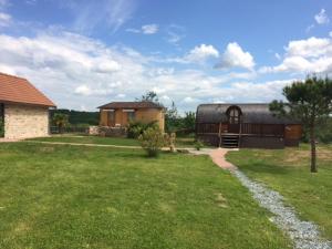 ein Hof mit einem Haus und einem Gebäude mit einem Rasenfeld in der Unterkunft Roulotte au domaine du Bouygues in Salvagnac-Cajarc